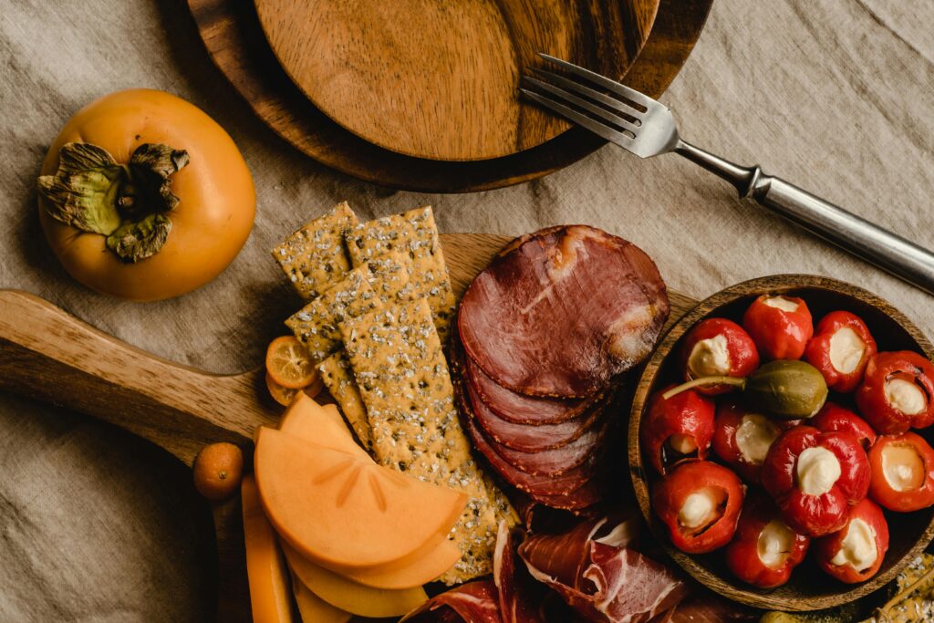 Assortiment de charcuterie, fromage, crackers et fruits sur une planche en bois.