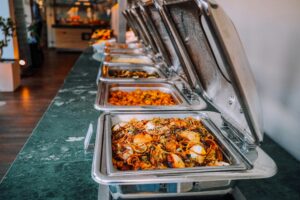 Buffet avec divers plats chauds dans des bacs en inox.